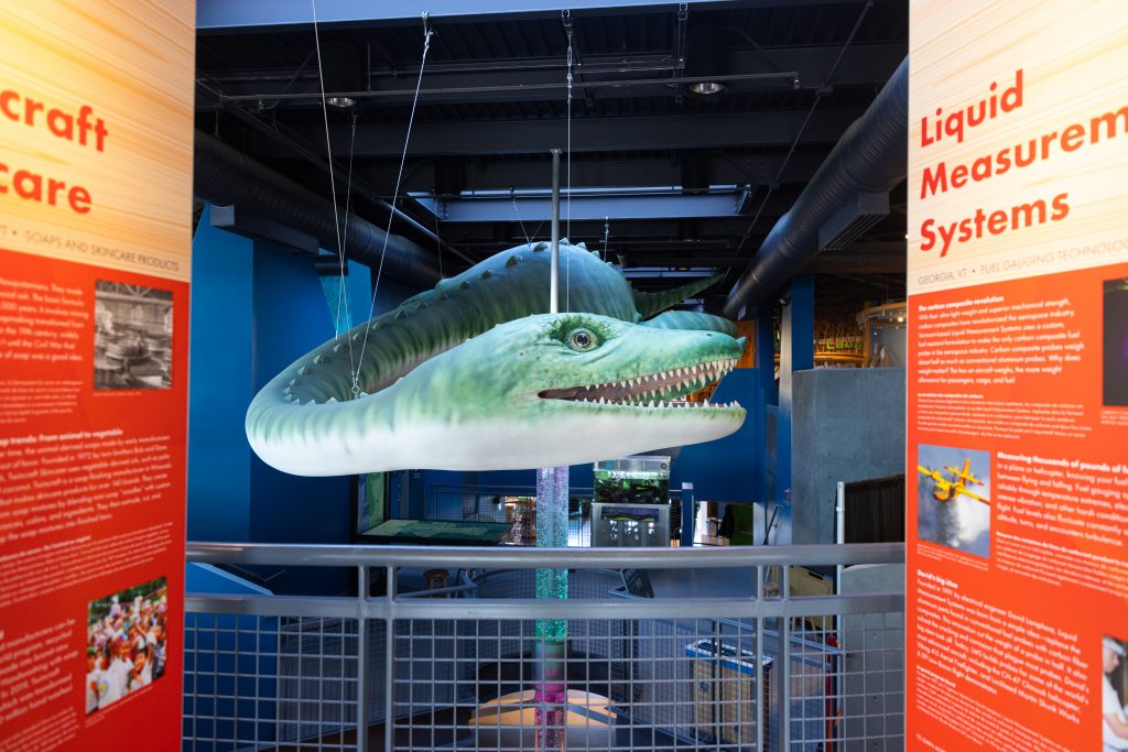 A view between two exhibit panels at ECHO's thirty-foot Champ sculpture, which hangs above the museum's mezzanine.