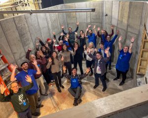 A group of about 20 ECHO staff standing inside the concrete form of an empty aquarium tank.