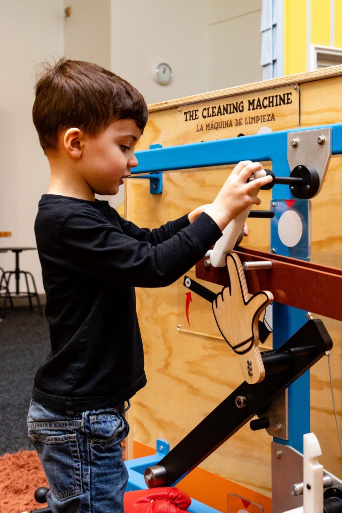 A child rearranges components of a Rube Goldberg Machine